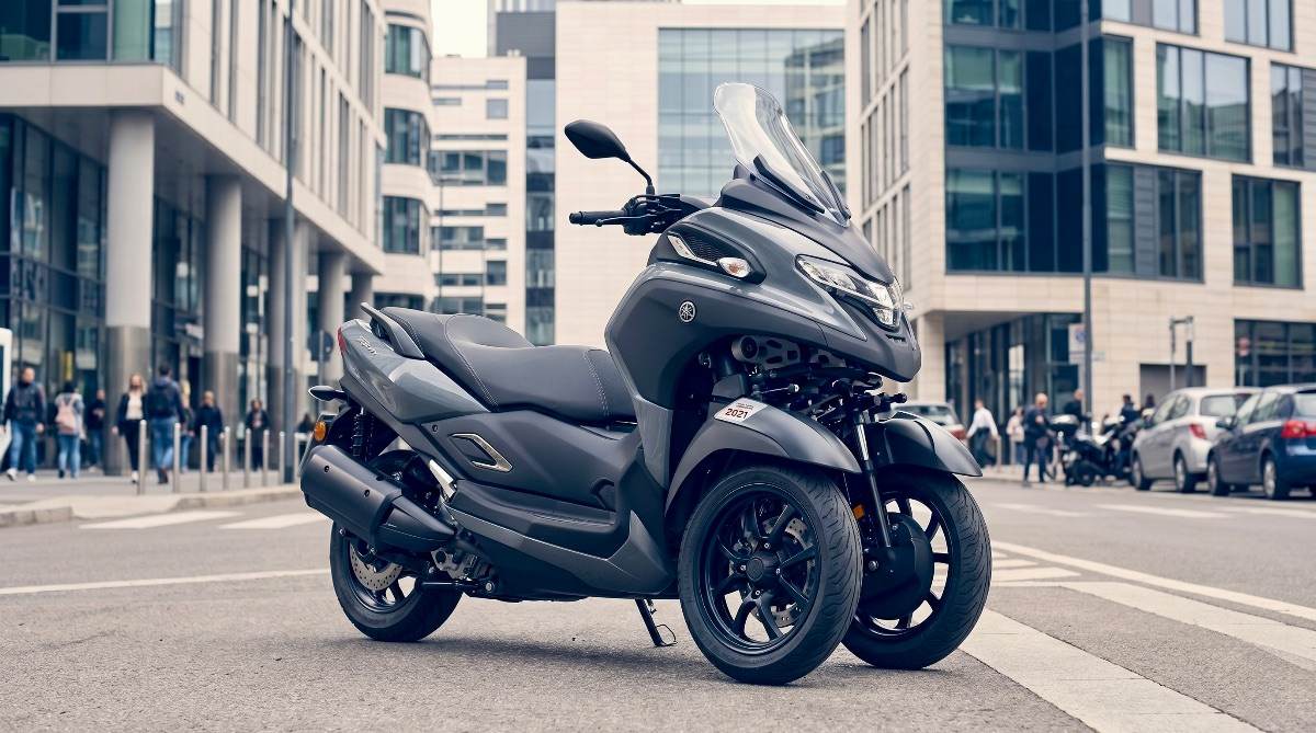 Yamaha Tricity 300 color azul circulando por una carretera escénica con montañas al fondo